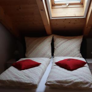 オールシュタットにあるFeWo Baderの赤い枕が備わる小さな部屋のベッド2台