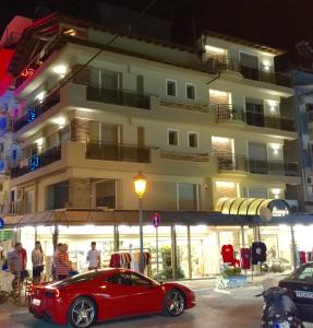 ein rotes Auto, das vor einem Gebäude parkt in der Unterkunft Sissy's Boutique Apartments in Paralia Katerinis