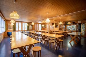a restaurant with wooden tables and chairs and lights at Simons Herberge in Meiringen
