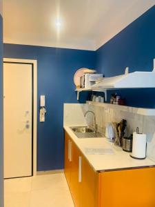 a kitchen with a sink and a blue wall at Petrus Studio with balcony in Thessaloniki