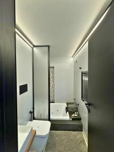 y baño con aseo, lavabo y bañera. en Dislocati BnB - Jacuzzi privata - Cucina - TV60" - Minimal Luxury, en Marigliano