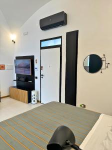 1 dormitorio con 1 cama y puerta con TV en Dislocati BnB - Jacuzzi privata - Cucina - TV60" - Minimal Luxury, en Marigliano