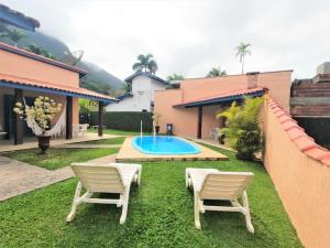 einen Garten mit zwei Stühlen und einem Pool in der Unterkunft Casa com piscina a 250m da praia! in Ubatuba