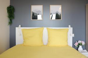 a bed with two yellow pillows and two pictures on the wall at LP - 4 saisons in Annecy