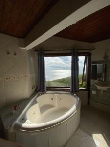 a large white tub in a bathroom with a window at Sentinelas do Mar in Arraial do Cabo