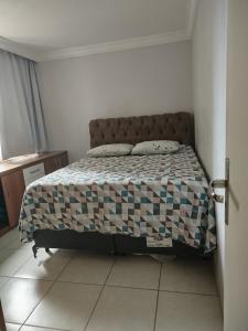 ein Schlafzimmer mit einem Bett mit einer karierten Decke in der Unterkunft Diamante in Guarapari