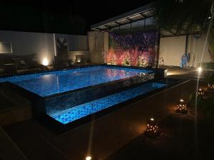 basen z niebieskimi światłami w ogrodzie w nocy w obiekcie 3 Bedroom Platinum Pool Villa Smooth as Silk w mieście Ban Khlong Haeng