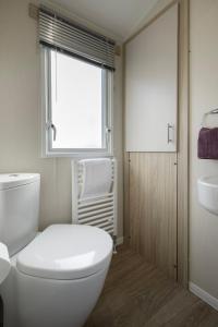 a bathroom with a toilet and a sink and a window at Ribble Heights Lodge - Cosy Pet-Free Countryside Retreat in Longridge