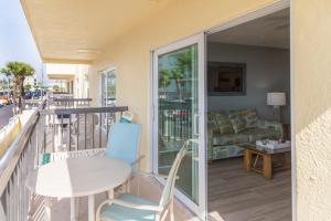 a balcony with a table and chairs and a couch at 239 Surf Song Resort in St. Pete Beach