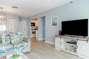 sala de estar con sofá y TV de pantalla plana en 239 Surf Song Resort, en St Pete Beach