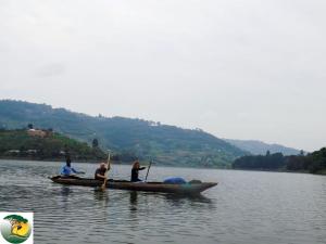 three people are rowing a boat on a lake at Antique cottages in Kabale