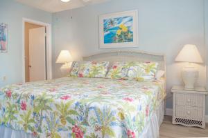 a bedroom with a bed with a floral bedspread and two lamps at 239 Surf Song Resort in St. Pete Beach