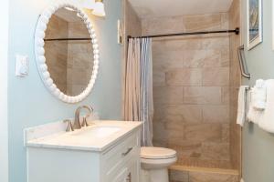 a bathroom with a toilet and a sink and a mirror at 239 Surf Song Resort in St. Pete Beach