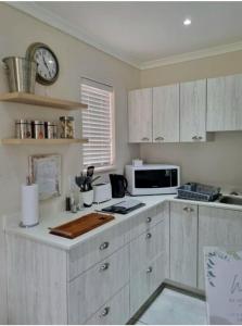 een keuken met witte kasten en een klok aan de muur bij Mon Rêve Estate in Kaapstad