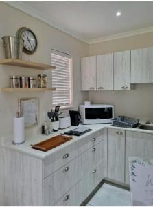 una cocina con armarios blancos y un reloj en la pared en Mon Rêve Estate, en Ciudad del Cabo