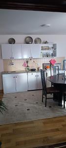 a kitchen with white cabinets and a table with chairs at Apartman Jamaković in Sarajevo