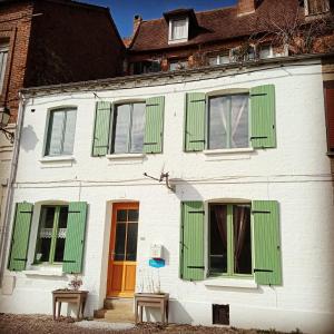 a white building with green shutters on it at Au Pied Des Remparts in Saint-Valery-sur-Somme