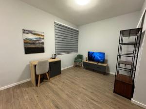 a room with a desk and a tv and a shelf at AVENUE Apartment 02 Tirana in Tirana