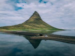 Una montaña con un coche estacionado junto al agua en Rent Campervans en Keflavík