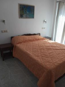 a bed with an orange comforter in a bedroom at Gerekos Studios and Apartments in Agios Georgios