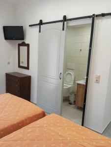 a bedroom with two beds and a bathroom with a toilet at Gerekos Studios and Apartments in Agios Georgios