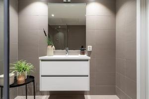 ein Badezimmer mit einem weißen Waschbecken und einem Spiegel in der Unterkunft Demims Apartments Greater Oslo - Modern, Central & Stylish in Lorenskog