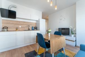 Apartament w Centrum في مينززدرويه: مطبخ مع طاولة خشبية وكراسي زرقاء