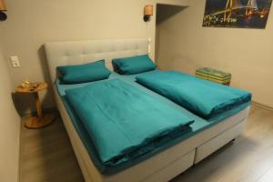 - un lit avec des draps et des oreillers bleus dans une chambre dans l'établissement Paris, à Schwandorf in Bayern