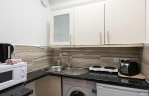 a kitchen with white cabinets and a sink at Central Hoxton Shoreditch in London