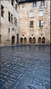 um grande edifício de tijolos com escrita no chão em Chambre au calme avec cuisine équipée sur demande en supplément em Figeac