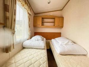 Duas camas num pequeno quarto com uma janela em 6 Berth Dog Friendly Caravan In Hunstanton In Norfolk Ref 13014l em Hunstanton
