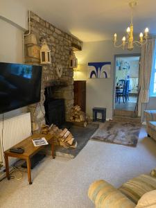 a living room with a stone fireplace and a tv at The Prophecy of Light Retreat in Glastonbury