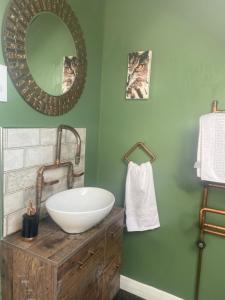 ein Bad mit einem Waschbecken und einem Wandspiegel in der Unterkunft The Prophecy of Light Retreat in Glastonbury