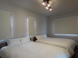 two beds in a room with two windows at Awajishima Cottage Hitotoki - Vacation STAY 10755v in Sumoto