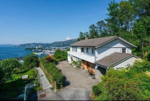a white house on a hill next to the water at Spacious villa with view - 5BR - FREE parking - Great Wi-Fi in Bergen