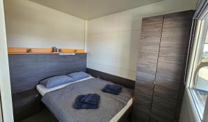 CHARTA mobile home Toni في بيروفاتش: غرفة نوم صغيرة عليها سرير ووسائد زرقاء