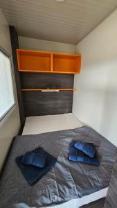ein kleines Schlafzimmer mit zwei blauen Kissen auf einem Bett in der Unterkunft CHARTA mobile home Toni in Pirovac