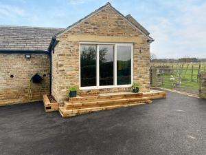 a stone house with a large window and a patio at Peartree Cottage in Sheffield