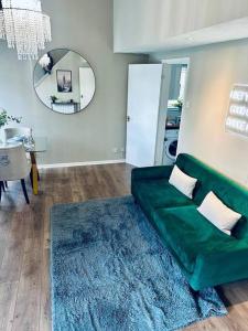 a living room with a green couch and a mirror at Delightful 1-bed Apt with Free Parking and Wi-fi by HP Accommodation in Milton Keynes