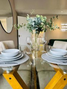 una mesa con platos y vasos y un jarrón con flores en Delightful 1-bed Apt with Free Parking and Wi-fi by HP Accommodation, en Milton Keynes