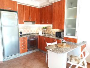 Una cocina con gabinetes de madera y un refrigerador de acero inoxidable. en HM Combarro, en Combarro