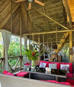 una sala de estar con muebles de color rojo y techo de madera. en Bungalows India & boutique, El Valle, Samana, en Santa Bárbara de Samaná