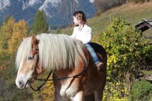 Une petite fille qui fait de l'équitation à l'arrière d'un cheval dans l'établissement Chalet Leo, à Michaelerberg