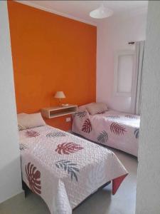 twee bedden in een kamer met een oranje muur bij LA CUECA in La Cieneguita