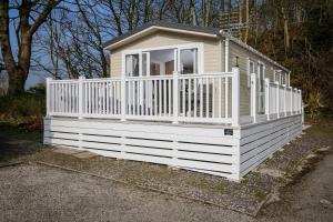 a small white house with a white fence at Ribble Heights - Cosy Tree-Top Glamping Lodge with Balcony in Longridge