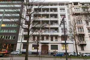Un edificio alto y blanco con coches aparcados delante. en Gmaison, en Milán