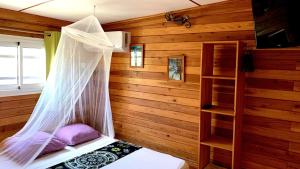 Schlafzimmer mit einem Bett mit Moskitonetz in der Unterkunft Cazadodo in L’Étang-Salé