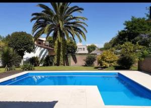 a swimming pool in front of a house with a palm tree at Chalet de ladrillos y tejas in La Plata