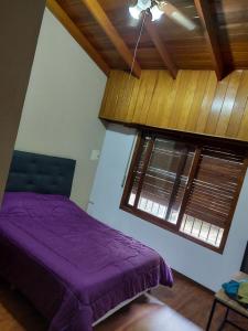 a bedroom with a purple bed and two windows at Chalet de ladrillos y tejas in La Plata