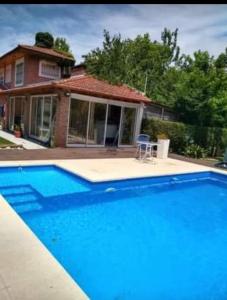 a large blue swimming pool in front of a house at Chalet de ladrillos y tejas in La Plata